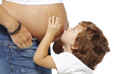 child kissing mums pregnant stomach