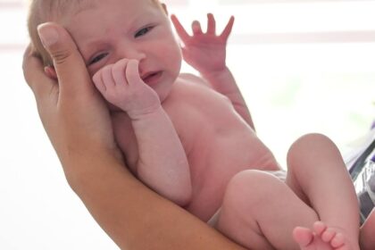 new born baby held in arms